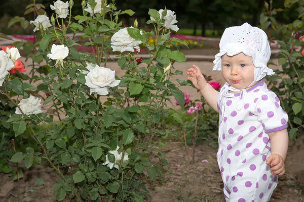 Sonriente niña bonita con flor rosa en el parque — Foto de Stock