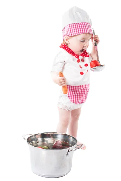 Baby Mädchen mit Kochmütze mit Gemüse und Pfanne isoliert auf weißem Hintergrund. Das Konzept der gesunden Ernährung und Kindheit — Stockfoto