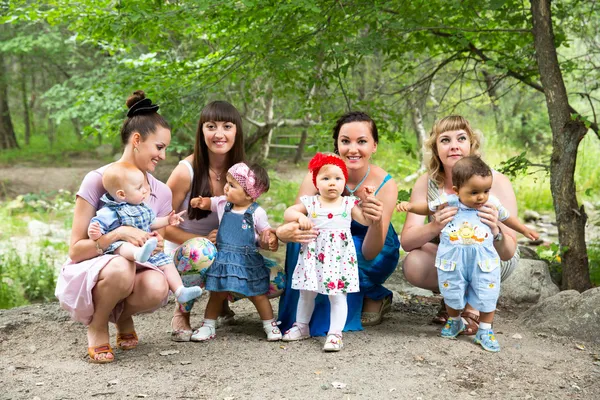 Quatro mães bonitas felizes e crianças abraçando e rindo. O conceito de infância e família . — Fotografia de Stock