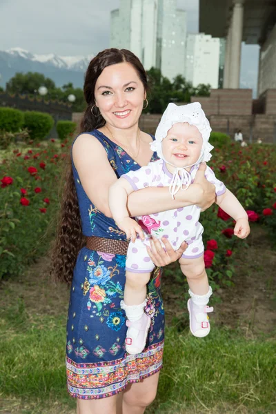 Gelukkig moeder en kind meisje knuffelen in bloemen. het concept van jeugd en familie. mooie moeder en haar baby buitenshuis — Stockfoto