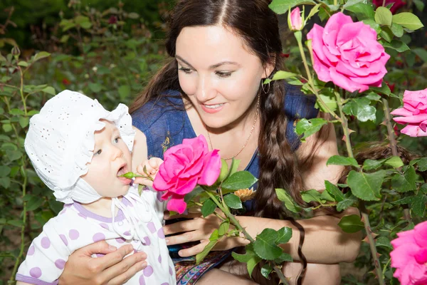 Glad mamma och barn flicka kramar i blommor. begreppet barndom och familj. vacker mor och hennes barn utomhus — Stockfoto