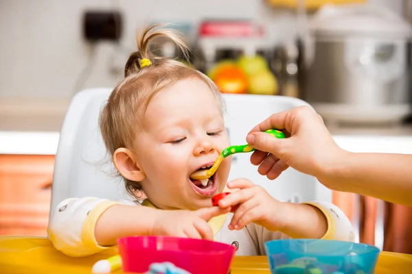 Child girl eats porridge from a spoon on kitchen. Use it for child, healthy food concept — Stock Photo, Image