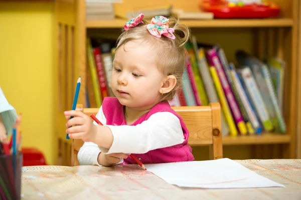 Menina bonito desenho com lápis coloridos na pré-escola à mesa no jardim de infância — Fotografia de Stock