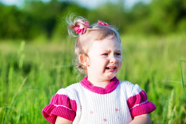 Little child girl  cry on grass on meadow. — Stock Photo, Image