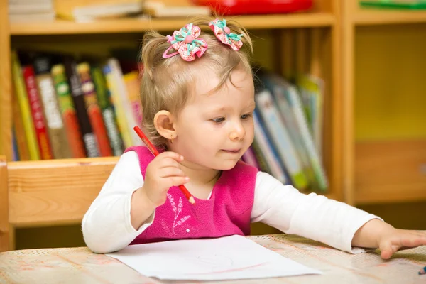 Dziecko dziewczynka rysunek z kolorowych ołówków w przedszkolu w tabeli. Mała dziewczynka i chłopiec w przedszkolu — Zdjęcie stockowe