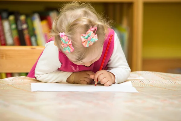 Дитяча дівчинка малює барвистими олівцями в дошкільному віці за столом. Маленька дівчинка і хлопчик малюють в дитячому садку — стокове фото
