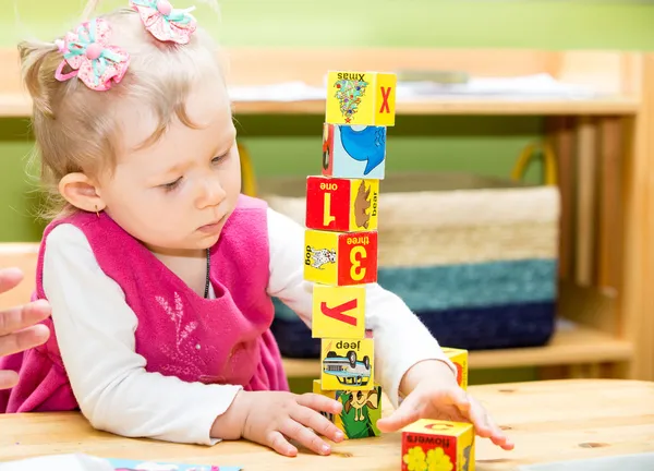 Kleines Mädchen spielt in Montessori-Vorschulklasse im Kindergarten mit Spielzeugbuchstaben und Zahlenblöcken. — Stockfoto