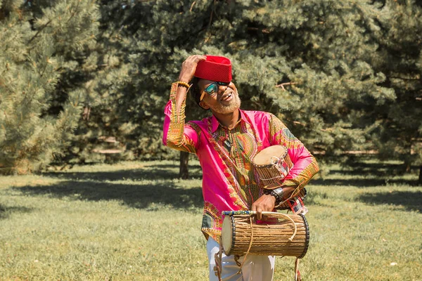 Schöner afrikanischer Mann in Nationaltracht spielt ethnische Trommel, Djembe. — Stockfoto