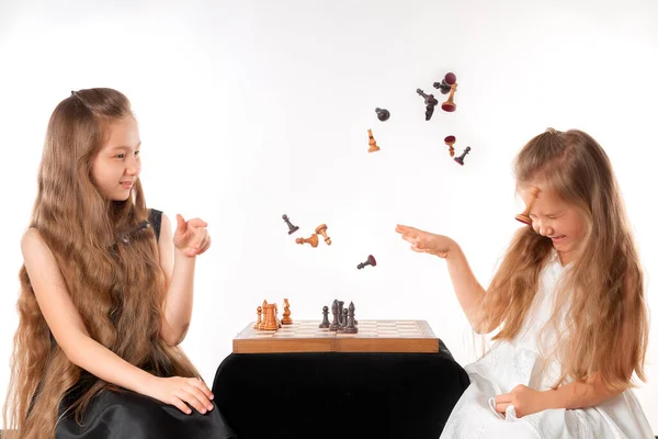 Little girls sisters play chess on white background. Sport and hobby concept. Cognitive development. Intellectual game. Smart children. — стоковое фото