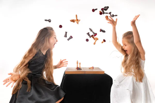 Little girls sisters play chess on white background. Sport and hobby concept. Cognitive development. Intellectual game. Smart children. —  Fotos de Stock