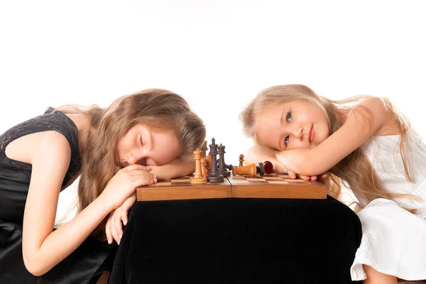 Little girls sisters play chess on white background. Sport and hobby concept. Cognitive development. Intellectual game. Smart children. — 스톡 사진