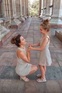 Güneşli bir yaz gününde, kızıyla birlikte gülümseyen mutlu anne. Anne ve kız şehirde kemerle dolaşıyorlar. Mutlu aile