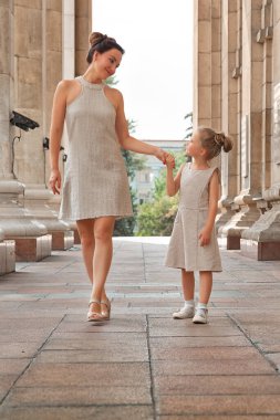 Güneşli bir yaz gününde, kızıyla birlikte gülümseyen mutlu anne. Anne ve kız şehirde kemerle dolaşıyorlar. Mutlu aile