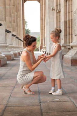 Güneşli bir yaz gününde, kızıyla birlikte gülümseyen mutlu anne. Anne ve kız şehirde kemerle dolaşıyorlar. Mutlu aile