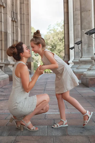 Güneşli bir yaz gününde, kızıyla birlikte gülümseyen mutlu anne. Anne ve kız şehirde kemerle dolaşıyorlar. Mutlu aile — Stok fotoğraf