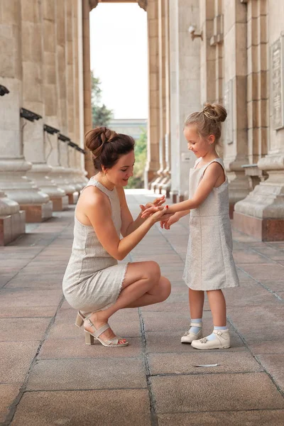 Happy smiling mom with a daughter child on a sunny summer day. Mother and girl kid walking around the city in the arch. Happy family — Stock Photo, Image