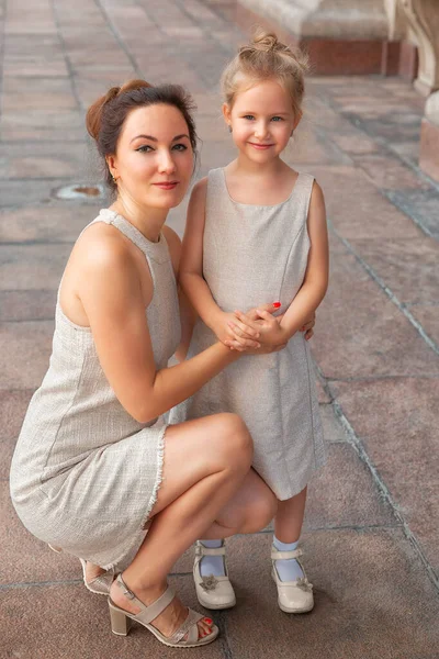 Happy smiling mom with a daughter child on a sunny summer day. Mother and girl kid walking around the city in the arch. Happy family — Stockfoto