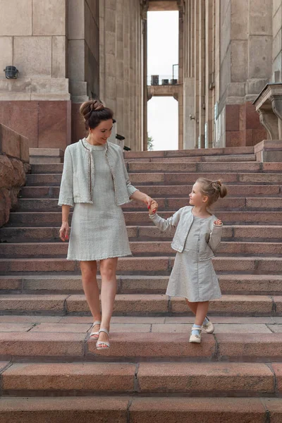 Güneşli bir yaz gününde, kızıyla birlikte gülümseyen mutlu anne. Anne ve kız şehirde kemerle dolaşıyorlar. Mutlu aile