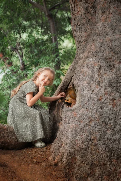 一个可爱的小女孩在大树上的画像 树上有松鼠 在森林里 — 图库照片