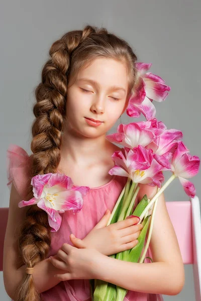灰色の背景に蘭の花と長い髪を持つ愛らしい少女の子供のクローズアップ肖像画 子供の顔 フロントビュー 家庭の概念では — ストック写真