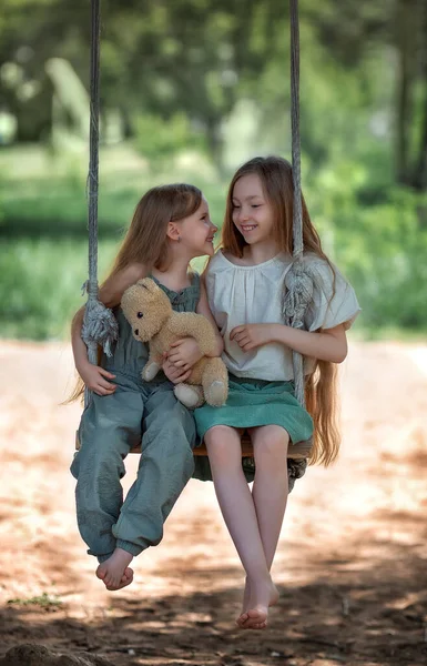 在阳光明媚的夏日 孩子们 长发的妹妹们在公园的操场上享受着带着玩具玩具玩具的秋千 — 图库照片
