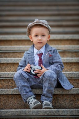 Dışarıdaki basamaklarda eski model fotoğraf makinesiyle fotoğraf çeken küçük bir çocuğun portresi. Çocuk fotoğraf çekimi. İnsanlar çocukluk yaşam tarzı konsepti.