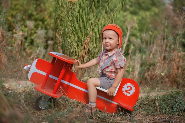 Szczęśliwy Chłopiec Pilot Siedzi Bawi Się Zabawkowym Czerwonym Samolotem Latem — Zdjęcie stockowe