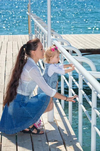 夏日阳光灿烂 快乐的妈妈带着女儿在河堤上散步 吉尔吉斯斯坦伊塞克湖的母亲和女童 快乐的家庭 — 图库照片