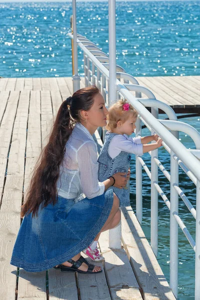 夏日阳光灿烂 快乐的妈妈带着女儿在河堤上散步 吉尔吉斯斯坦伊塞克湖的母亲和女童 快乐的家庭 — 图库照片