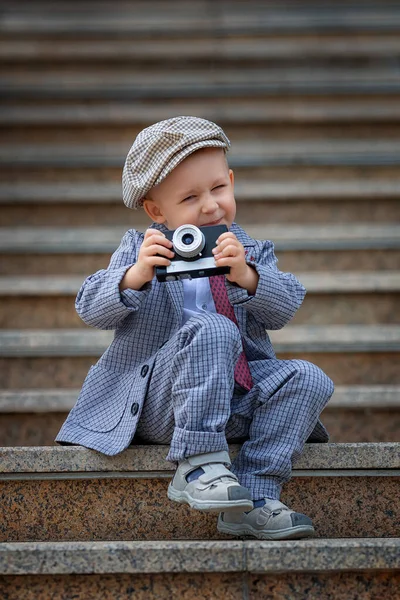 Dışarıdaki basamaklarda eski model fotoğraf makinesiyle fotoğraf çeken küçük bir çocuğun portresi. Çocuk fotoğraf çekimi. İnsanlar çocukluk yaşam tarzı konsepti.