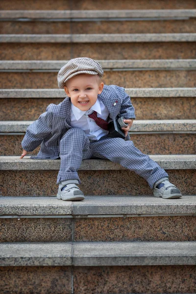 Dışarıdaki basamaklarda eski model fotoğraf makinesiyle fotoğraf çeken küçük bir çocuğun portresi. Çocuk fotoğraf çekimi. İnsanlar çocukluk yaşam tarzı konsepti.