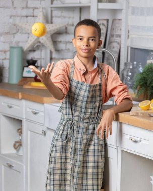 Evdeki mutfakta taze limon pişiren zenci çocuk. Afrikalı çocuk hazırlanıyor. Sağlıklı salata hazırlığı. Çiğ malzemeler masada. Aile iletişimi, aşçılık ve hafta sonu tatili.