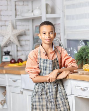 Evdeki mutfakta taze limon pişiren zenci çocuk. Afrikalı çocuk hazırlanıyor. Sağlıklı salata hazırlığı. Çiğ malzemeler masada. Aile iletişimi, aşçılık ve hafta sonu tatili.
