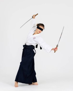Geleneksel samuray hakama kimonosuyla Aikido üstadı kadın. Kılıçlı siyah kuşak, beyaz arka planda katana. Sağlıklı yaşam tarzı ve spor anlayışı.