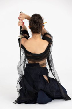 Geleneksel samuray hakama kimonosuyla Aikido üstadı kadın. Kılıçlı siyah kuşak, beyaz arka planda katana. Sağlıklı yaşam tarzı ve spor anlayışı.