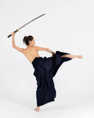 Geleneksel samuray hakama kimonosuyla Aikido üstadı kadın. Kılıçlı siyah kuşak, beyaz arka planda katana. Sağlıklı yaşam tarzı ve spor anlayışı.