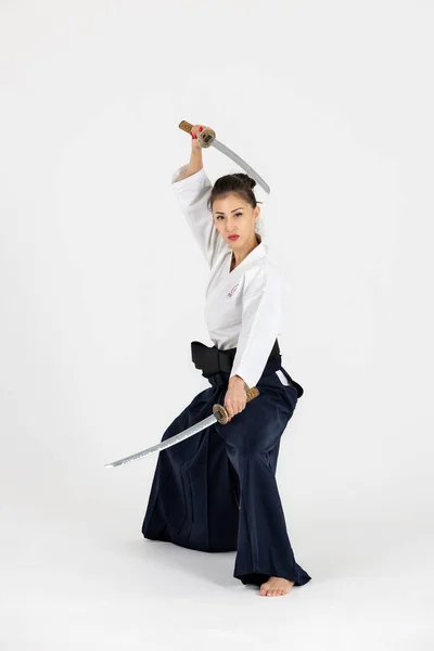 白を背景に黒帯刀 刀を持つ伝統的な武家袴姿の合気道マスター女性 健康的なライフスタイルとスポーツのコンセプト — ストック写真