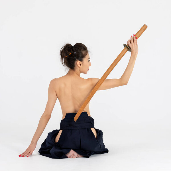Aikido master woman in traditional samurai hakama kimono with black belt with wooden sword bokken, katana on white background. Healthy lifestyle and sports concept.
