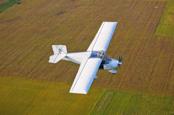 An airplane flying above the fields — Stock Photo, Image