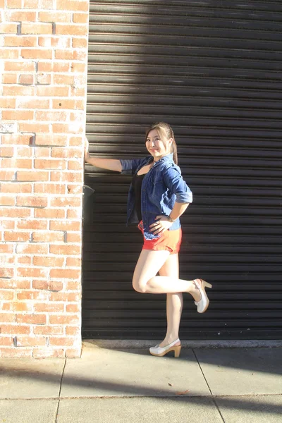 Modelo asiático posando na frente da porta da garagem . — Fotografia de Stock