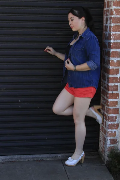 Modelo asiático posando na frente da porta da garagem . — Fotografia de Stock