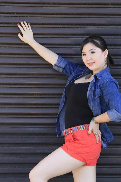 Modelo asiático posando na frente da porta da garagem . — Fotografia de Stock