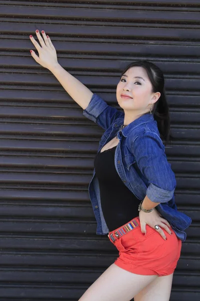 Modelo asiático posando na frente da porta da garagem . — Fotografia de Stock