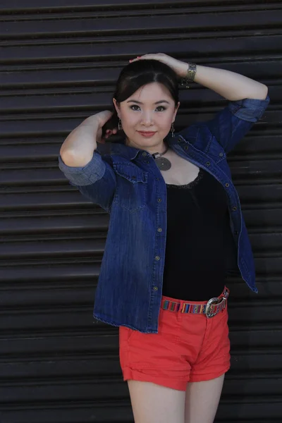 Modelo asiático posando na frente da porta da garagem . — Fotografia de Stock