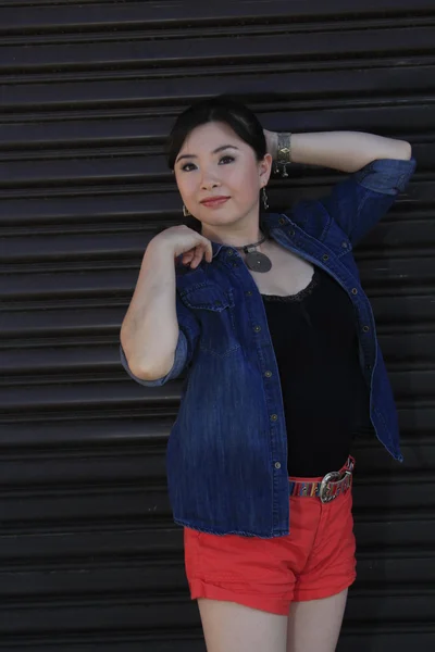 Modelo asiático posando na frente da porta da garagem . — Fotografia de Stock