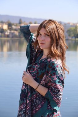 Gölün önünde güzel elbiseli güzel beyaz bir kızın fotoğrafı.