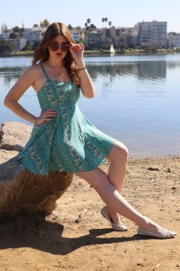 Gölün önünde güzel elbiseli güzel beyaz bir kızın fotoğrafı.