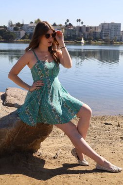 Gölün önünde güzel elbiseli güzel beyaz bir kızın fotoğrafı.