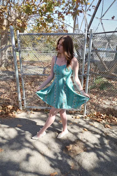 フェンスの前の美しいドレスを着た美しい白い女の子の写真 — ストック写真