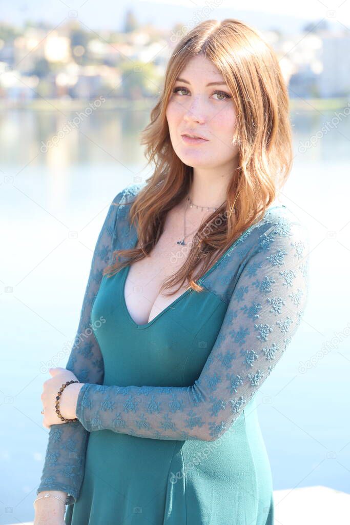 Photo of a Beautiful white girl in a beautiful dress in front of a lake